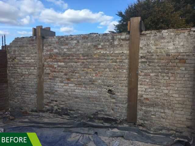 A weathered brick wall supported by two vertical wooden beams. The wall shows signs of age, with cracks and discoloration. A bright blue sky with scattered clouds is visible above. A green BEFORE label is at the bottom left corner.